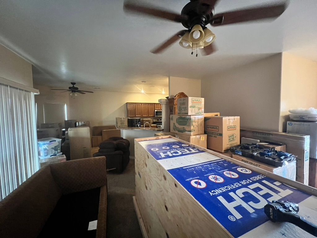 A living room filled with boxes and a ceiling fan.