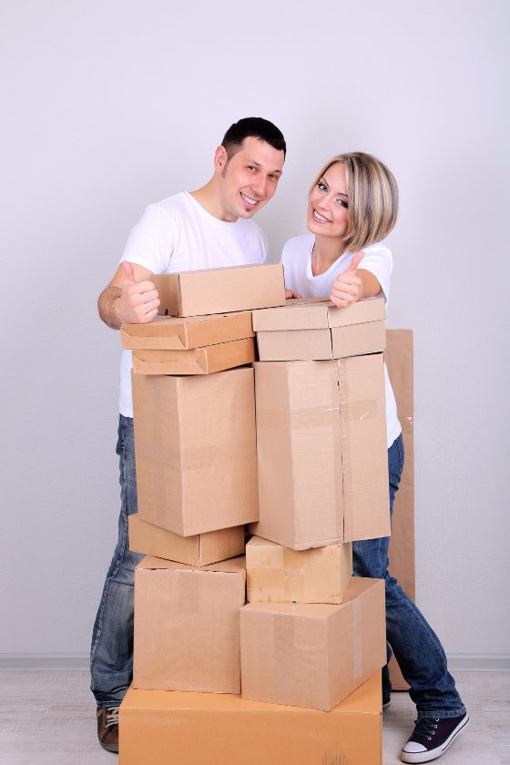 A man and a woman are standing next to a pile of cardboard boxes.