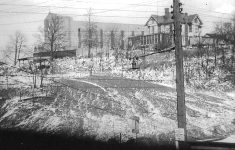 Snowy street with utility pole and houses on a hillside in winter