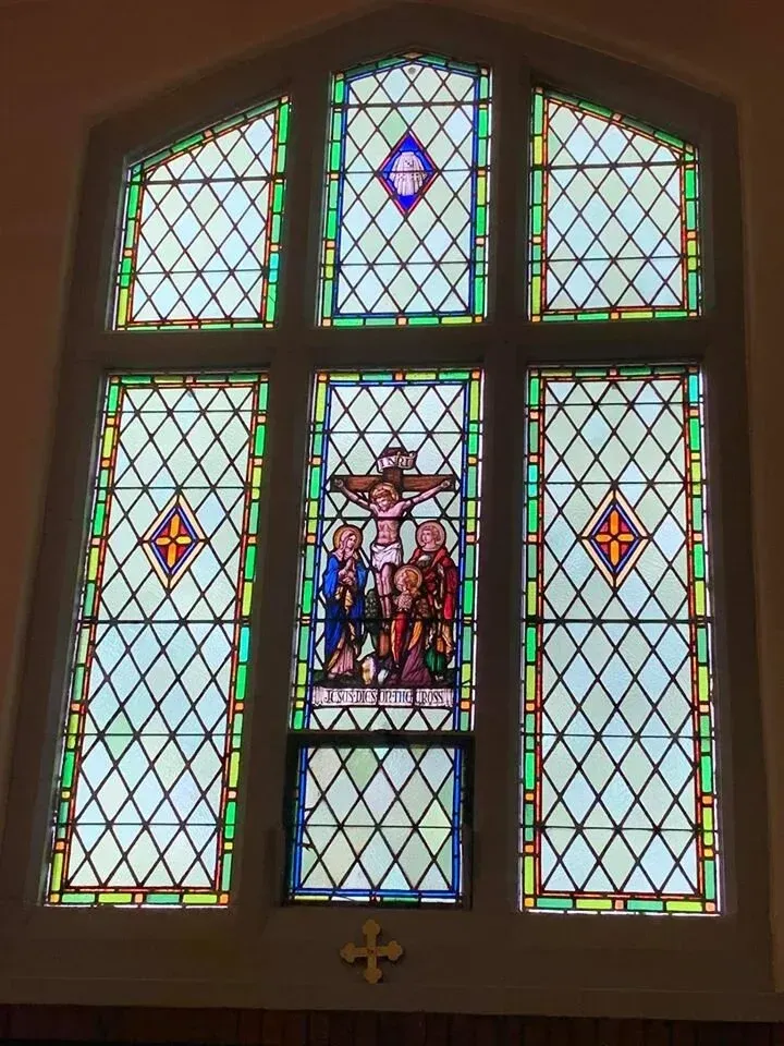 Stained glass church window with colorful geometric panels and a central religious scene.