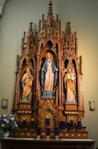 Ornate church altar with statues of Mary and saints, featuring gold carvings and blue accents.