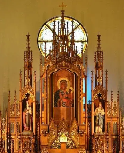 Ornate church altar with gold Gothic carvings, central icon, and stained glass rose window
