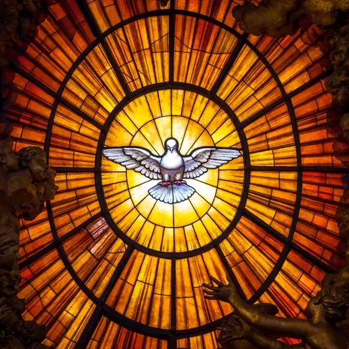 Stained glass dove with outstretched wings glowing in warm orange and gold light