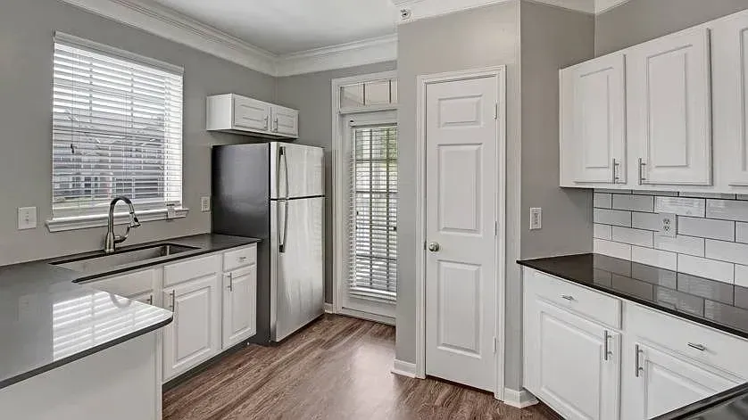 Modern kitchen with stainless steel refrigerator, white cabinets, dark countertops, and subway tile backsplash at Woodland Pointe in Nashville, TN.