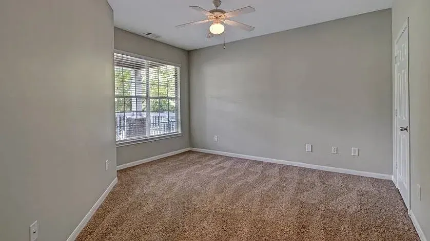 Empty bedroom with a ceiling fan and blinds on the window at Woodland Pointe in Nashville, TN.