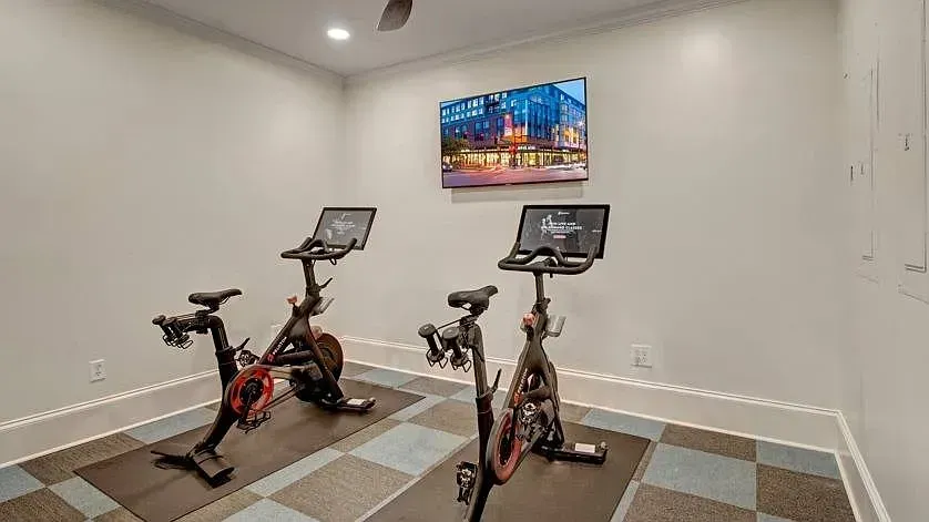 Spin bikes in a fitness room with a large screen displaying a building at Woodland Pointe in Nashville, TN. 