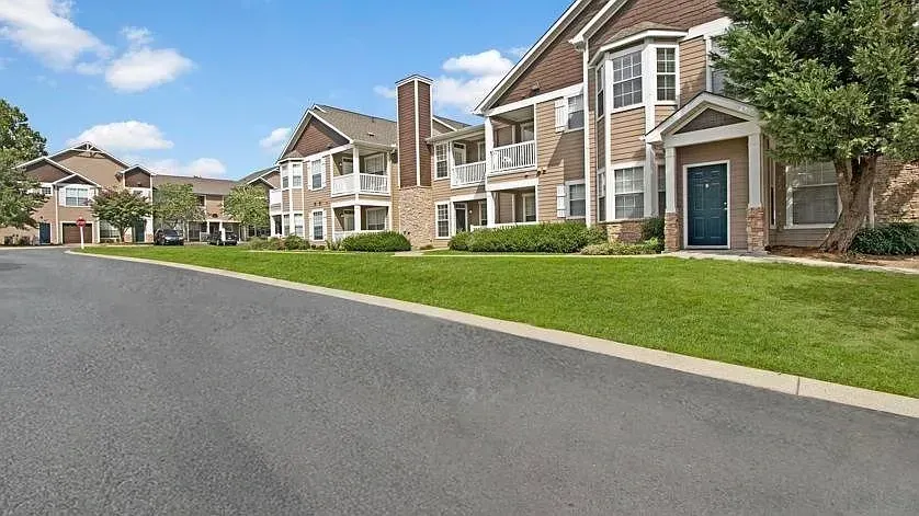 Exterior of apartment buildings with green lawns and a paved road at Woodland Pointe in Nashville, TN.