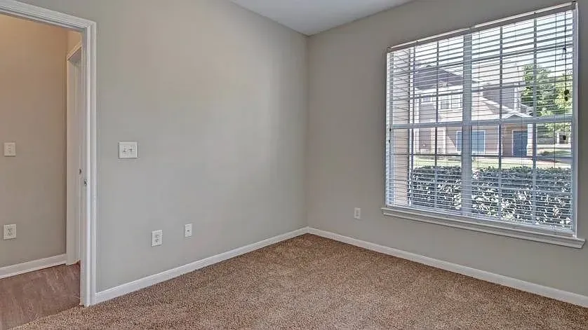 Empty bedroom with plush carpet and a large window at Woodland Pointe in Nashville, TN.