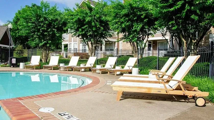 Outdoor swimming pool area with lounge chairs and trees at Woodland Pointe in Nashville, TN.