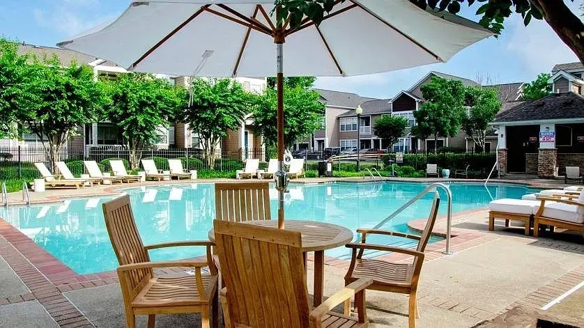 Outdoor swimming pool area with lounge chairs, umbrellas, and seating.