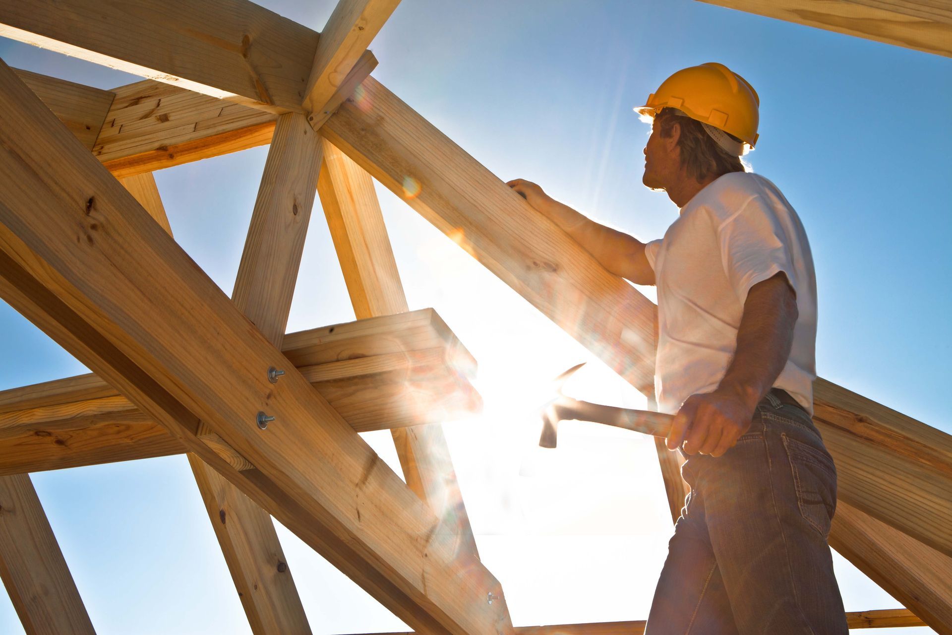 A man wearing a hard hat is working on a wooden structure