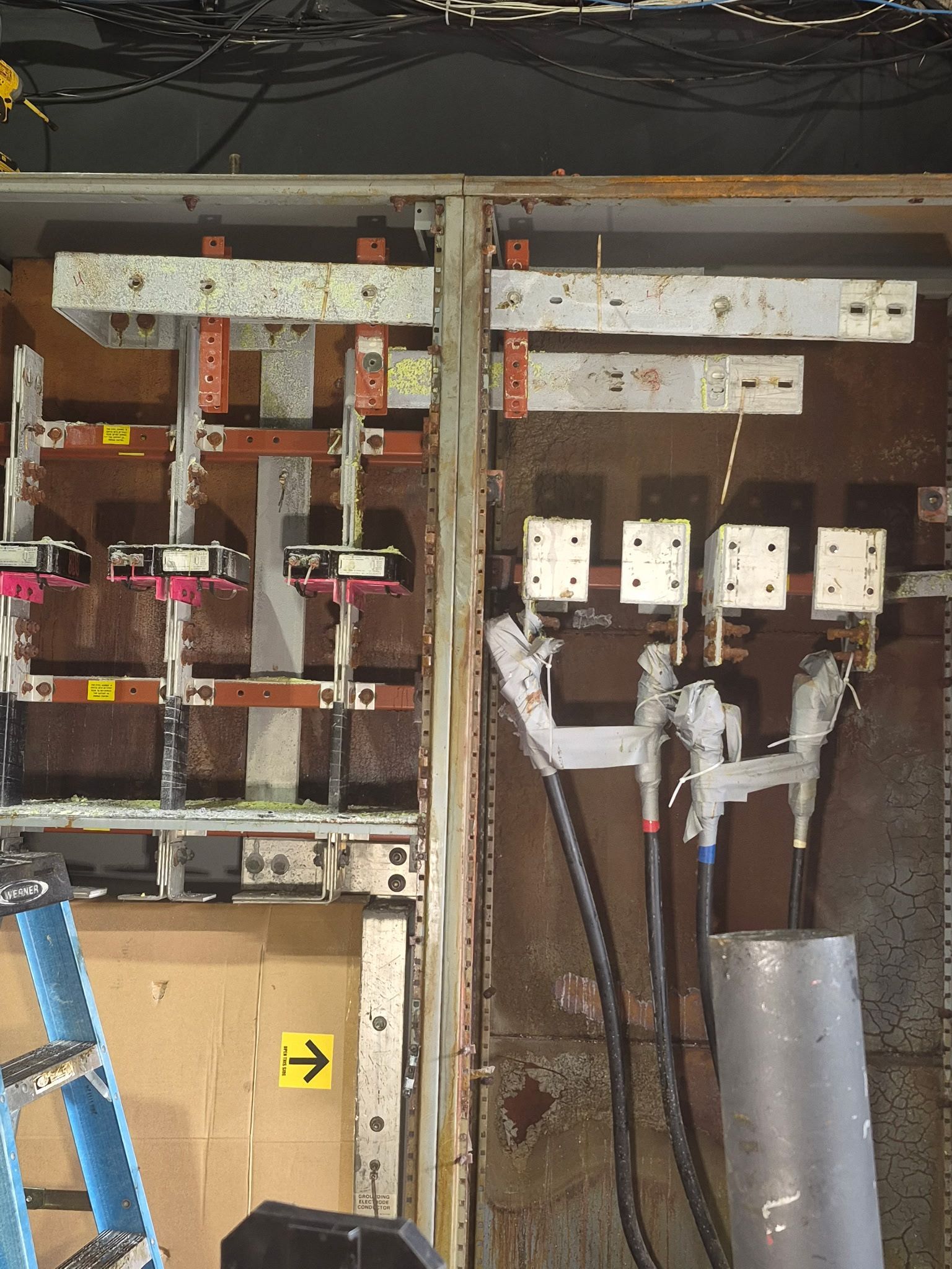 Interior view of an industrial electrical panel with copper busbars and heavy-duty power cables attached.
