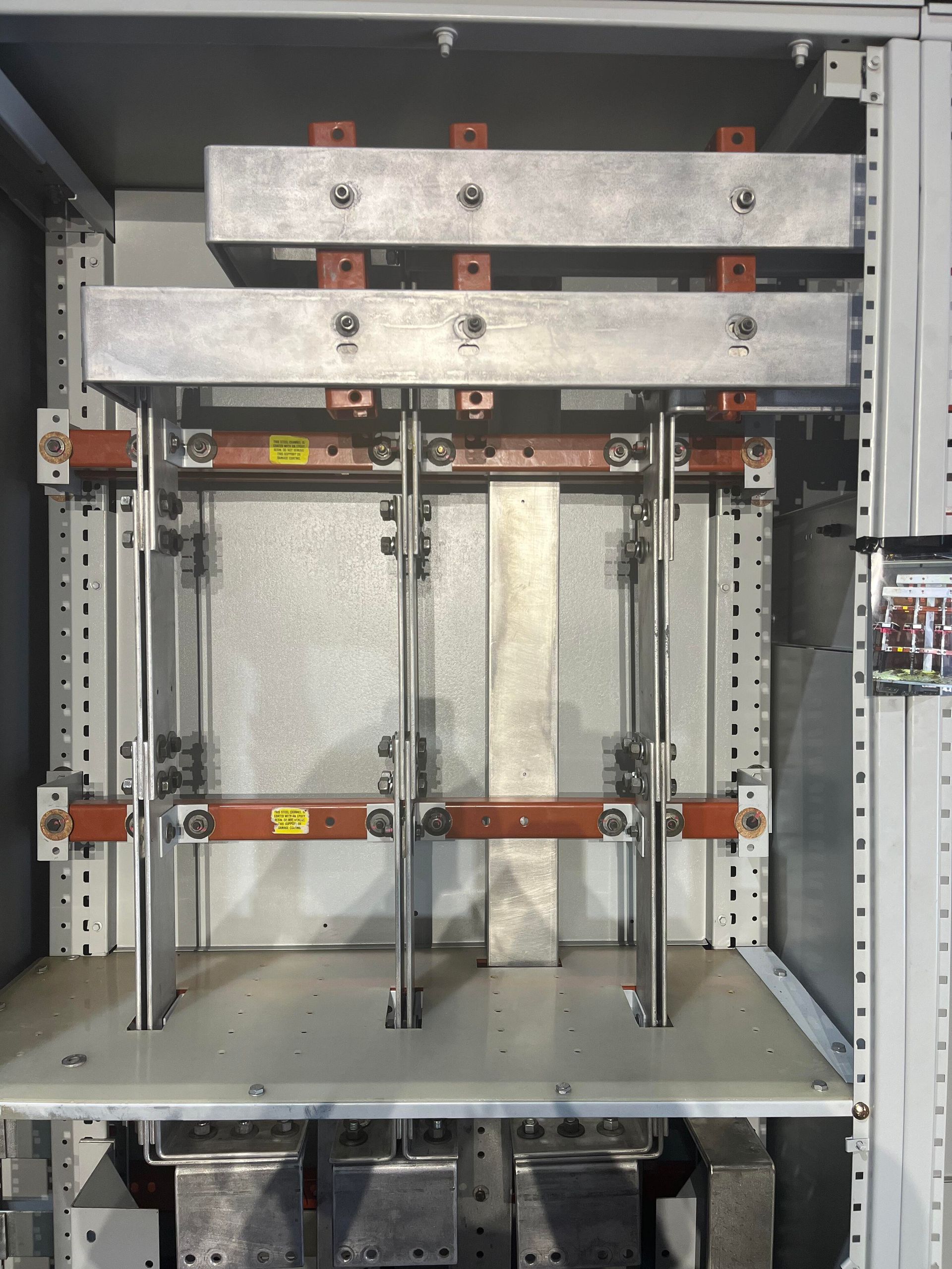 Electrical switchgear cabinet interior with metallic busbars, insulators, and heavy-duty power distribution components.