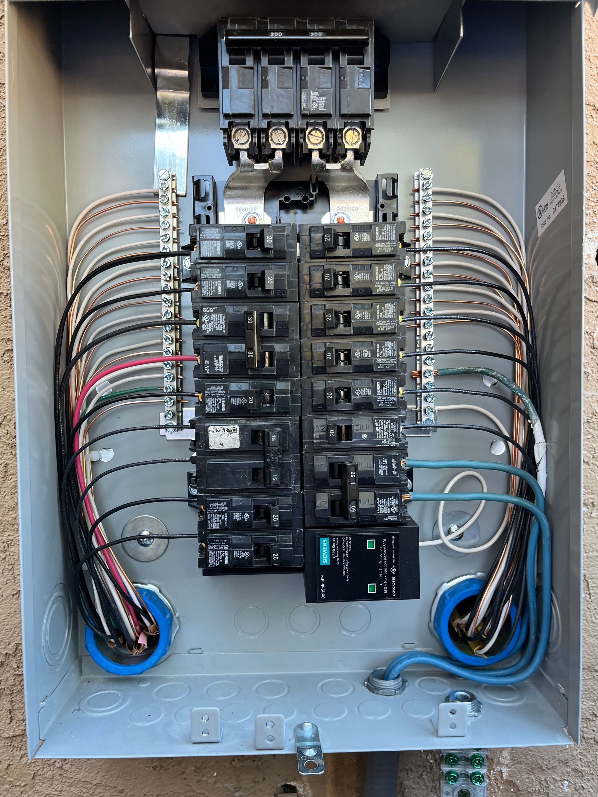 An open residential electrical breaker panel with multiple circuit breakers and black and white wiring connected.