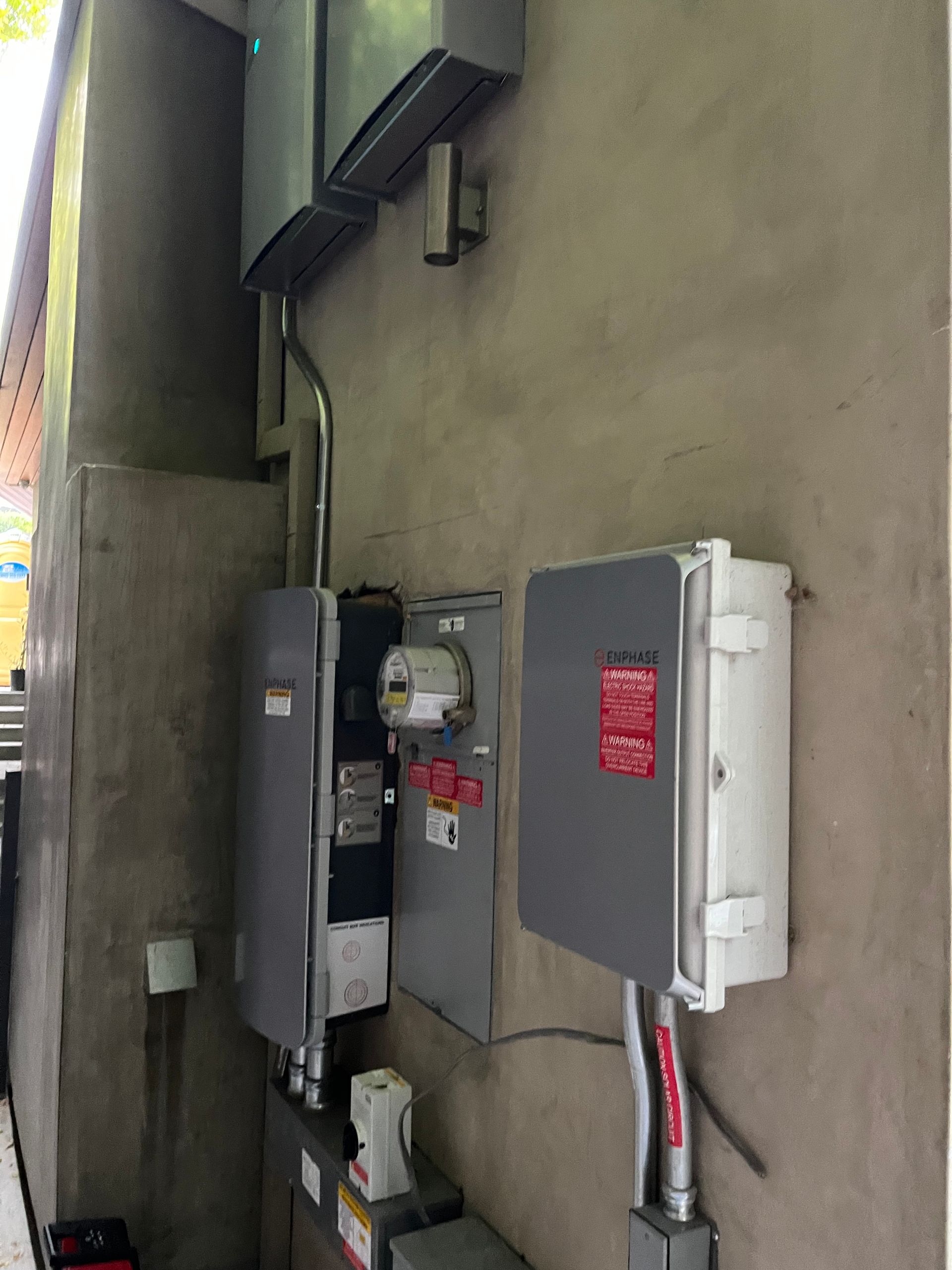 Electrical equipment boxes, including a meter and disconnect switches, mounted on an exterior concrete wall.
