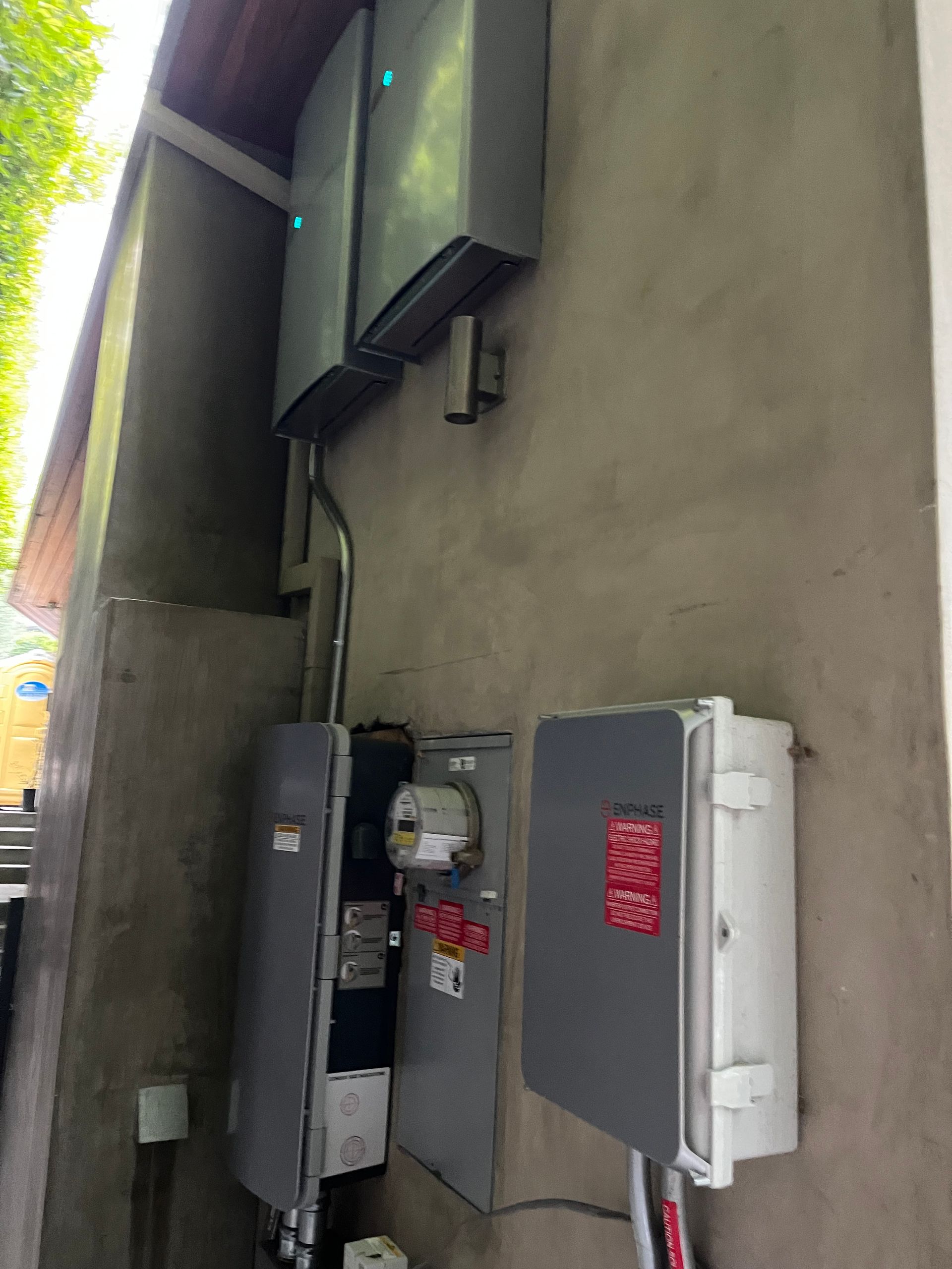 Wall-mounted electrical and solar inverter equipment installed on an outdoor concrete wall.
