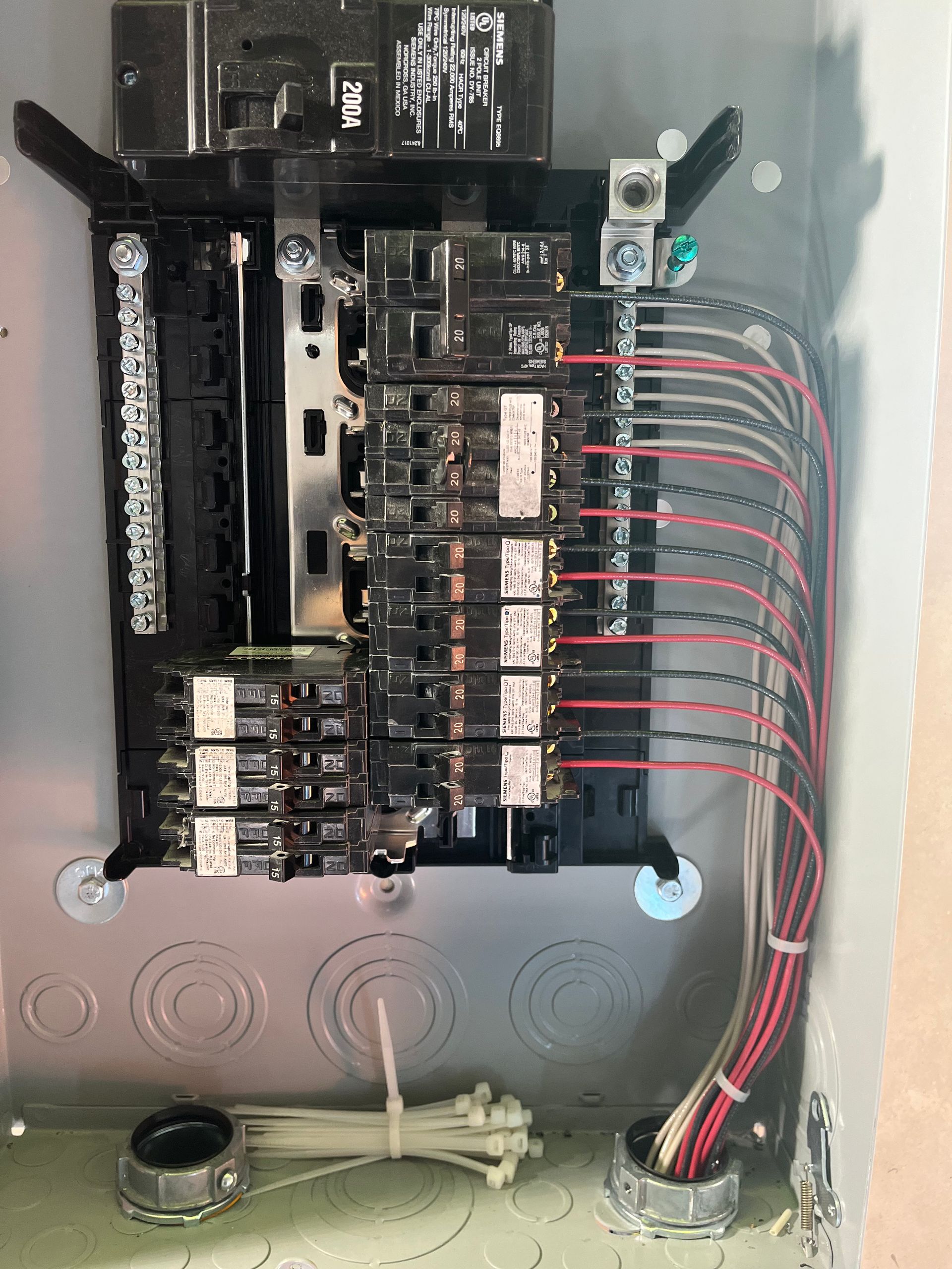 Open electrical service panel with two columns of black circuit breakers and neatly routed red, black, and white wiring.