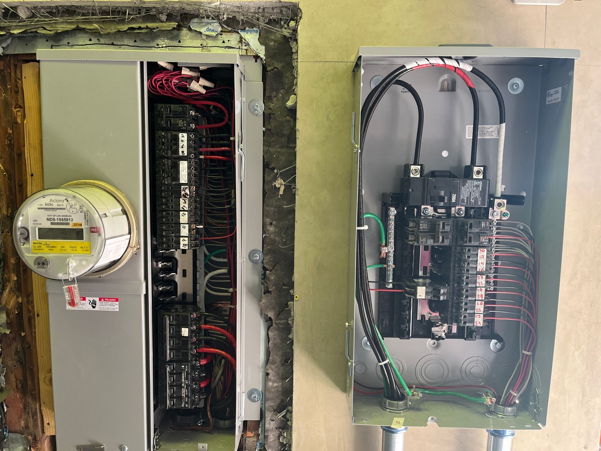 Two electrical panels side-by-side; the left unit features an electric meter, and the right unit displays internal wiring.