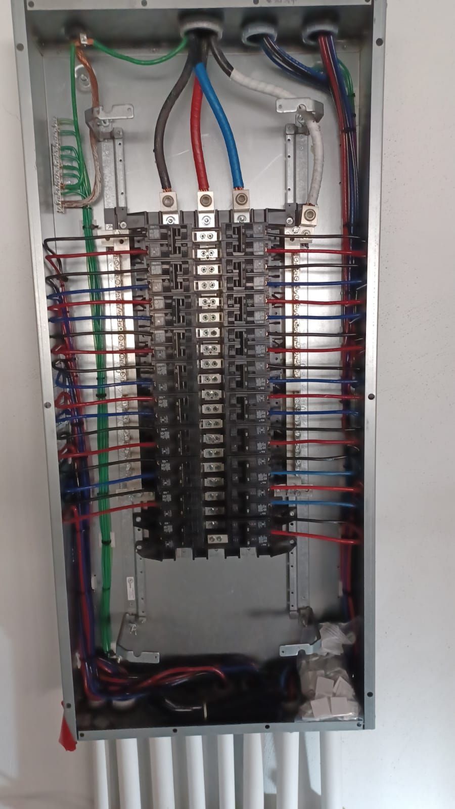 An open electrical panel with multicolored wires connected to rows of circuit breakers.