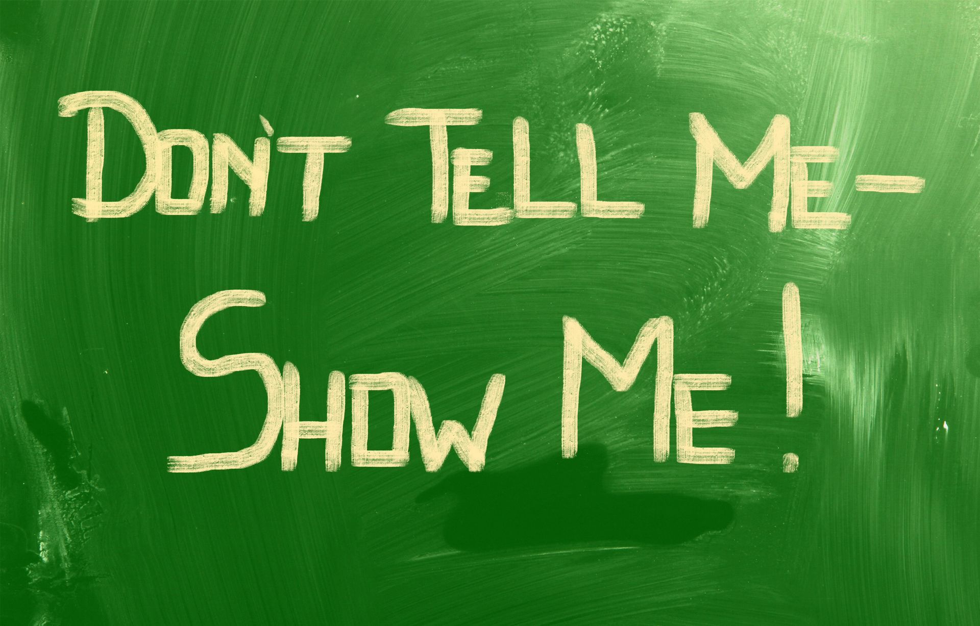 Groen bord met daarop in gele krijtletters de tekst 'Don't Tell Me - Show Me!.