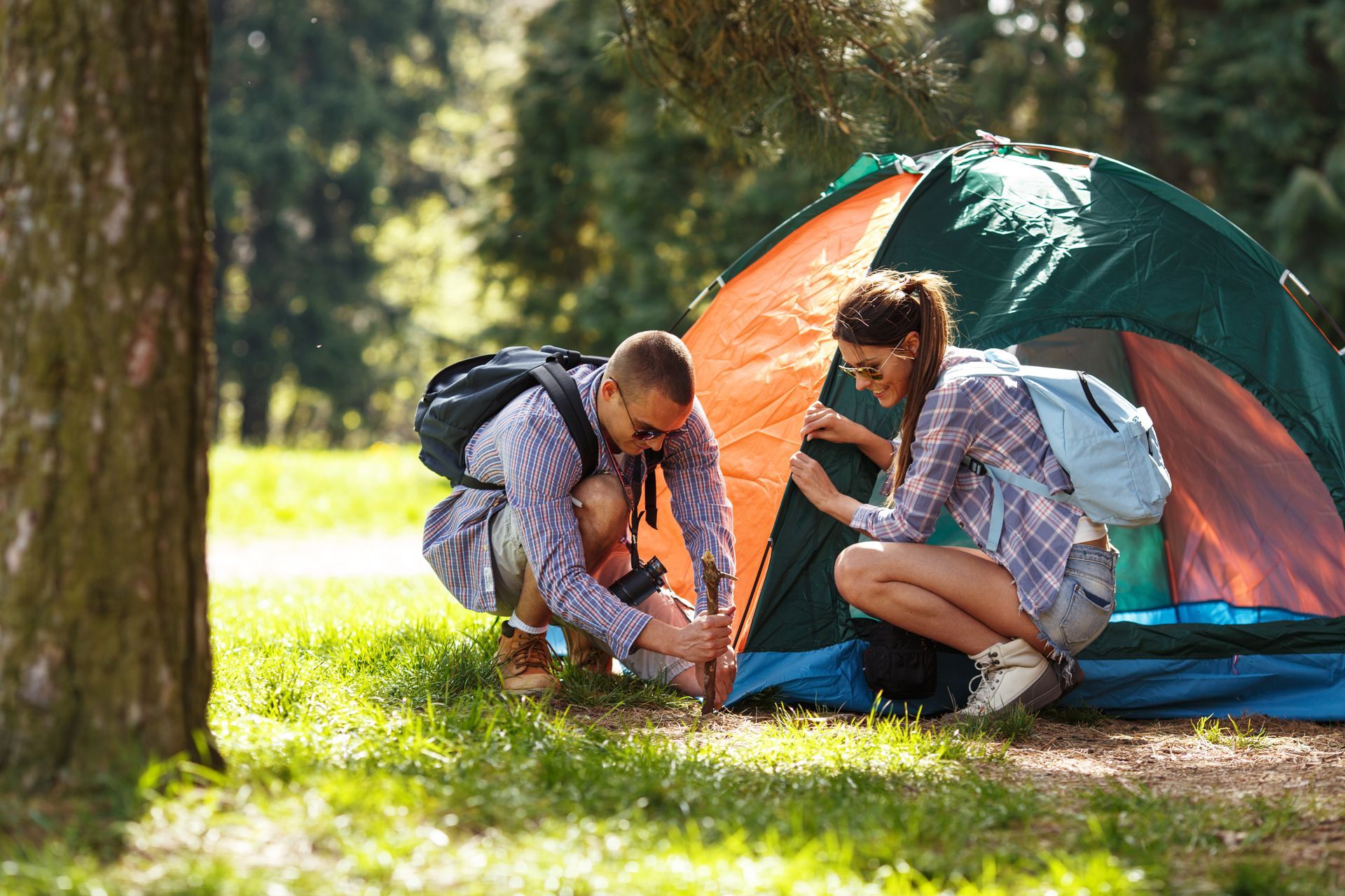 Couple setting up a tent in the forest—perfect starter experience for first-time campers with Camp in a Box gear.