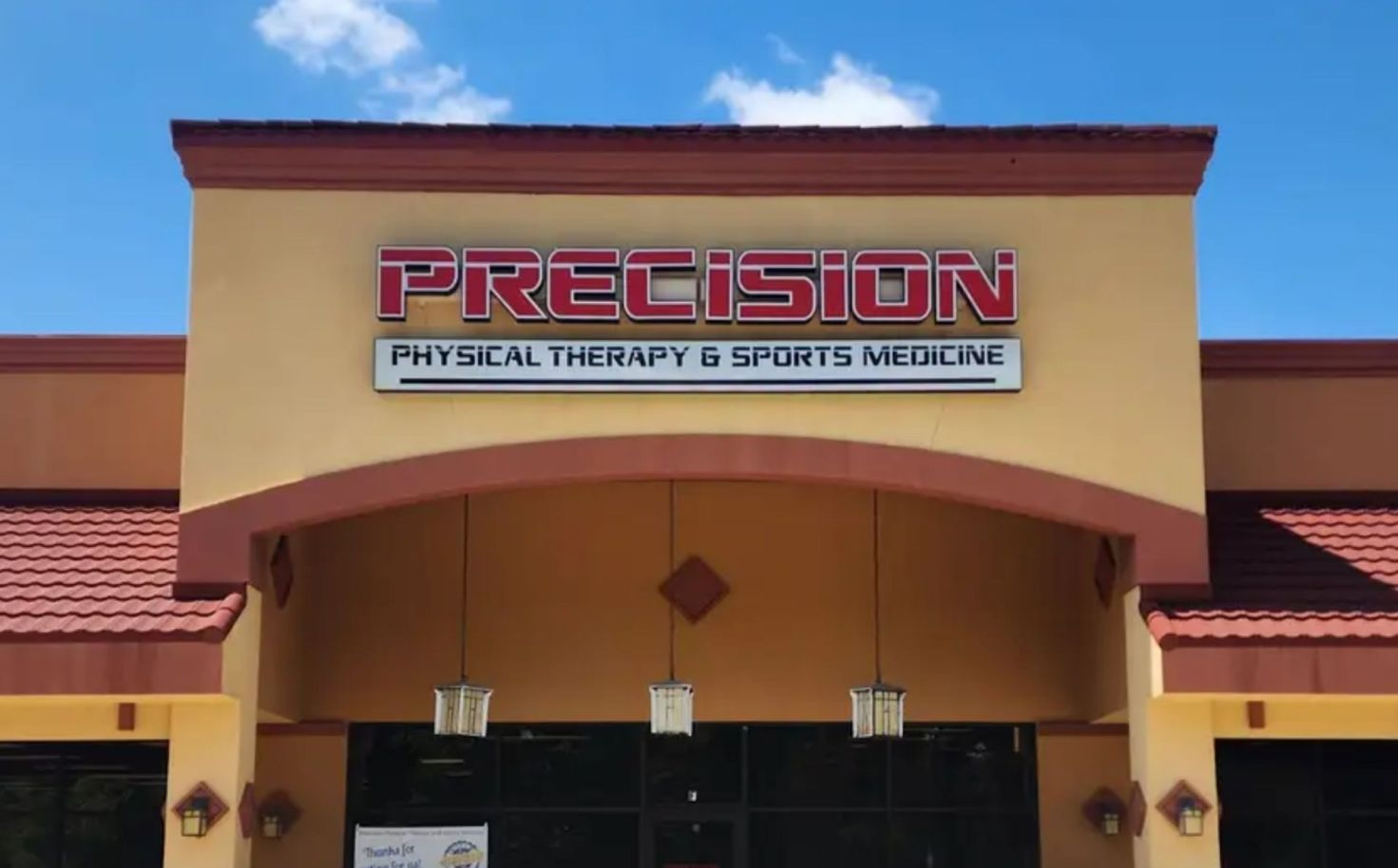 Exterior of Precision Physical Therapy in Village Oaks, tan building, red sign, blue sky.