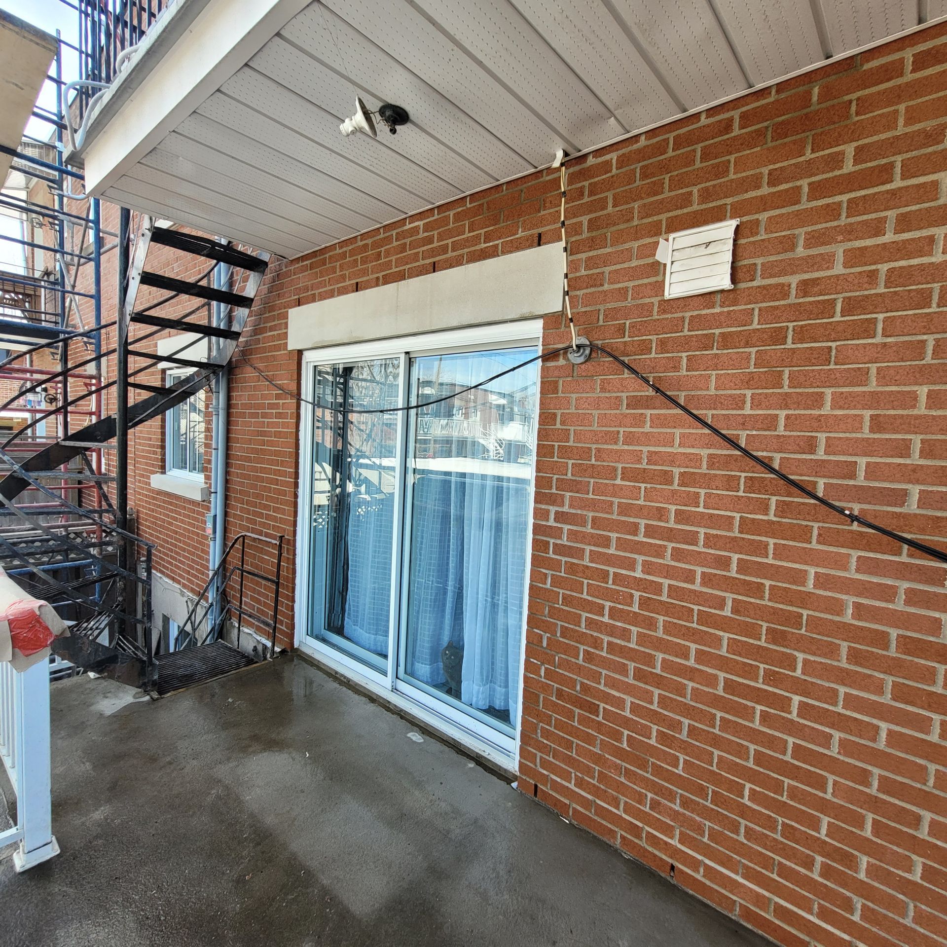 Un bâtiment en briques avec une porte coulissante en verre et des escaliers