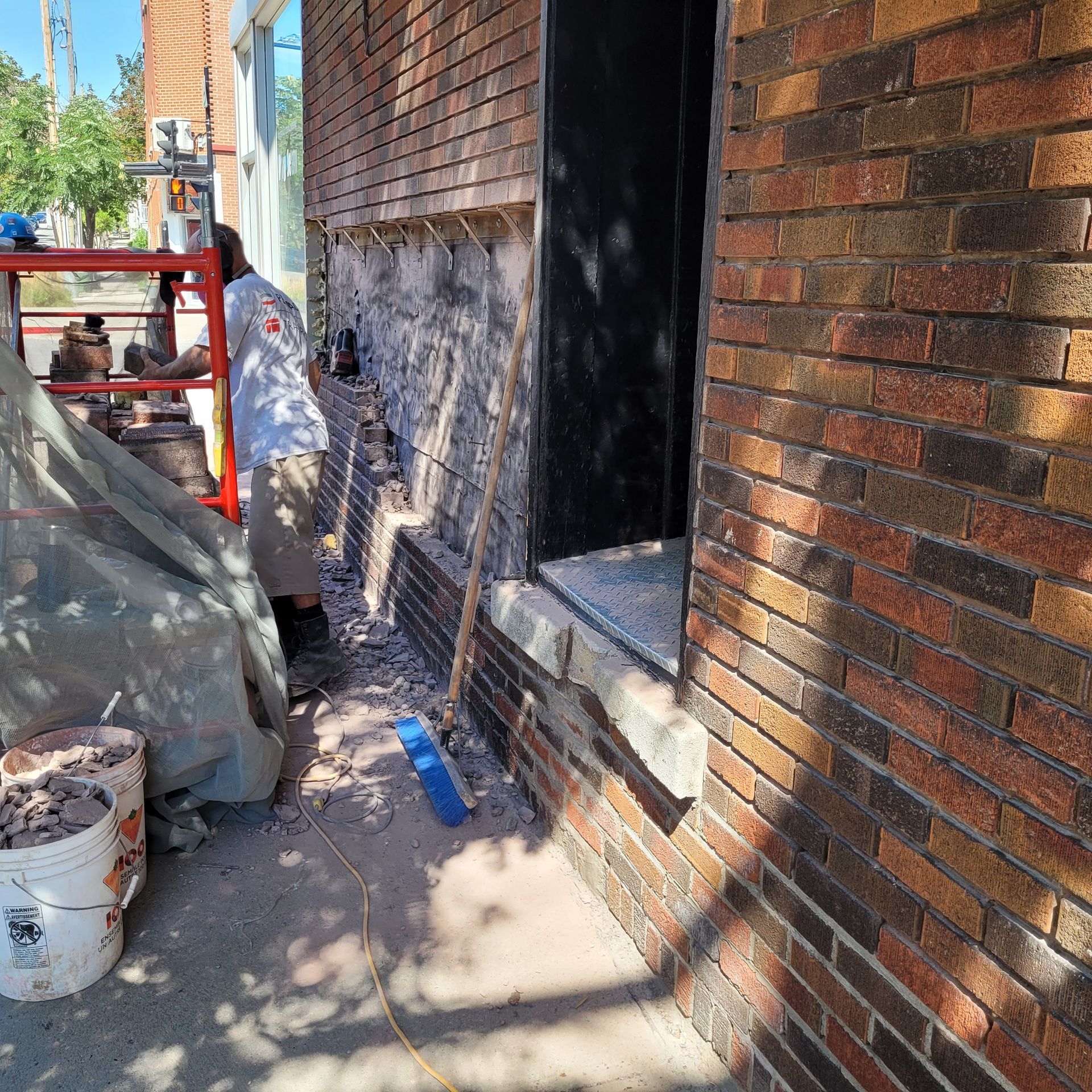 Un homme travaille sur le côté d'un bâtiment en briques