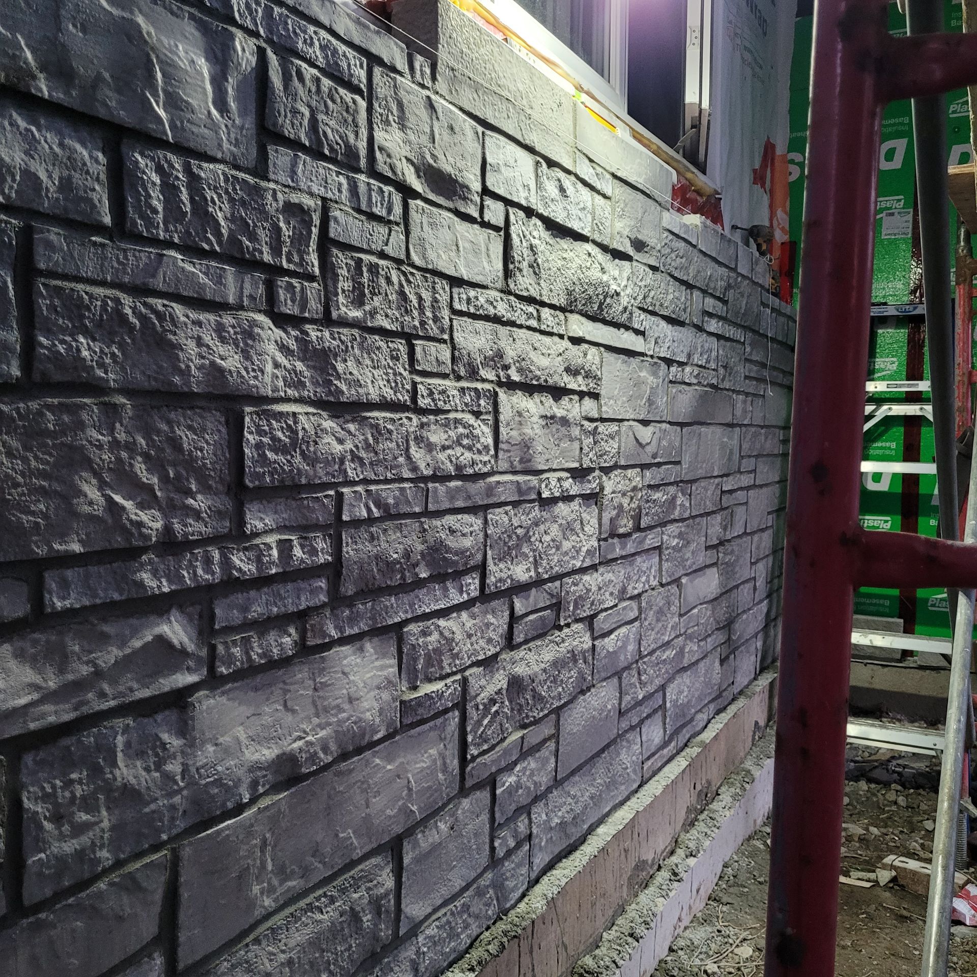 Un mur de briques avec une fenêtre et un échafaudage en arrière-plan