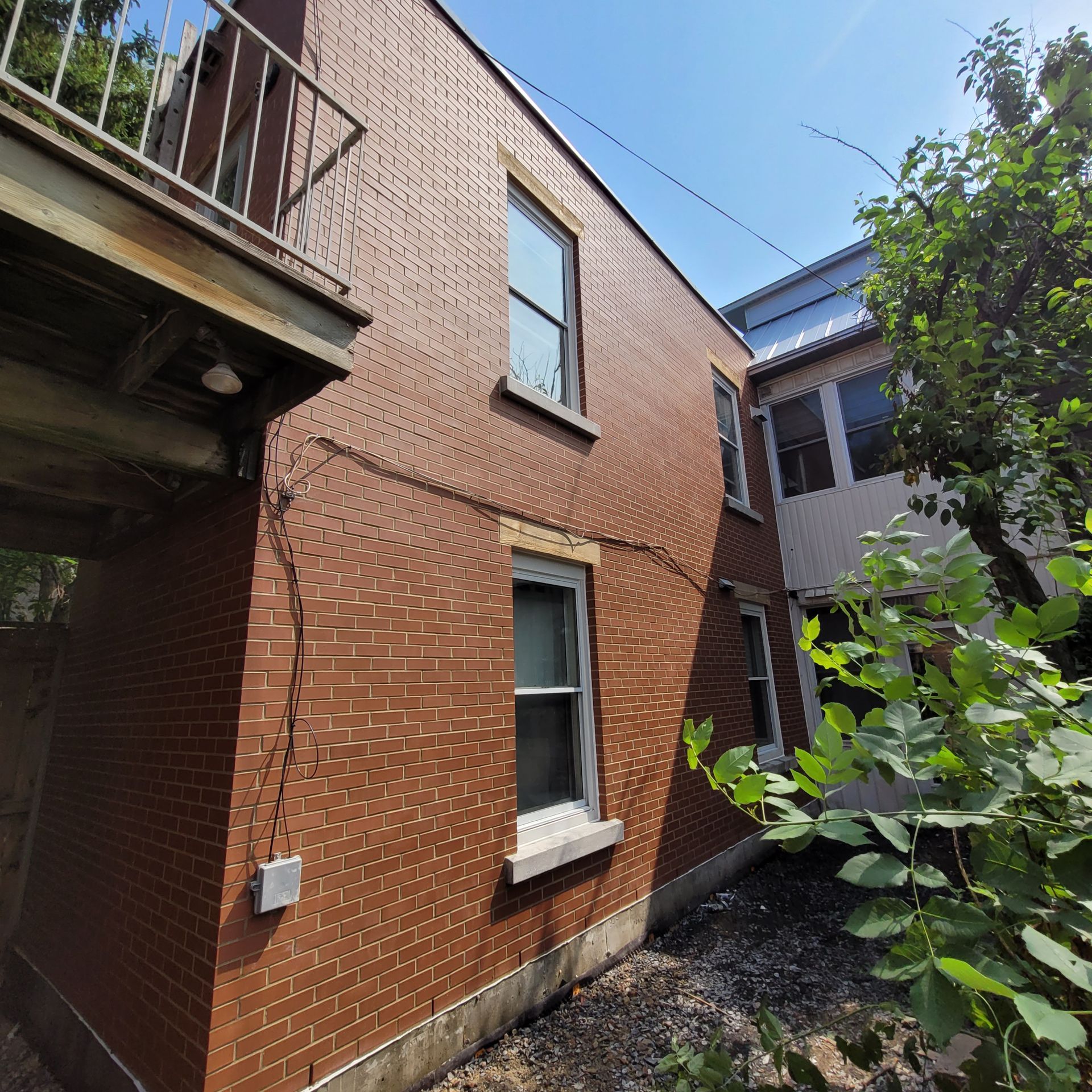 Un bâtiment en briques avec un balcon et un arbre devant