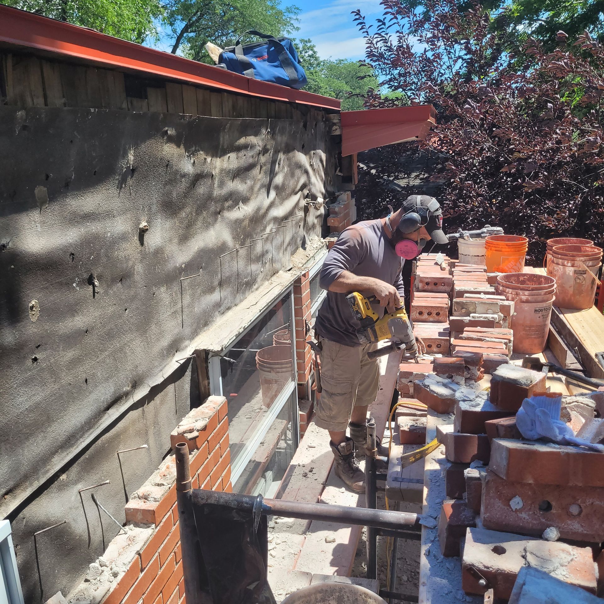 Un homme portant un masque travaille sur un mur de briques