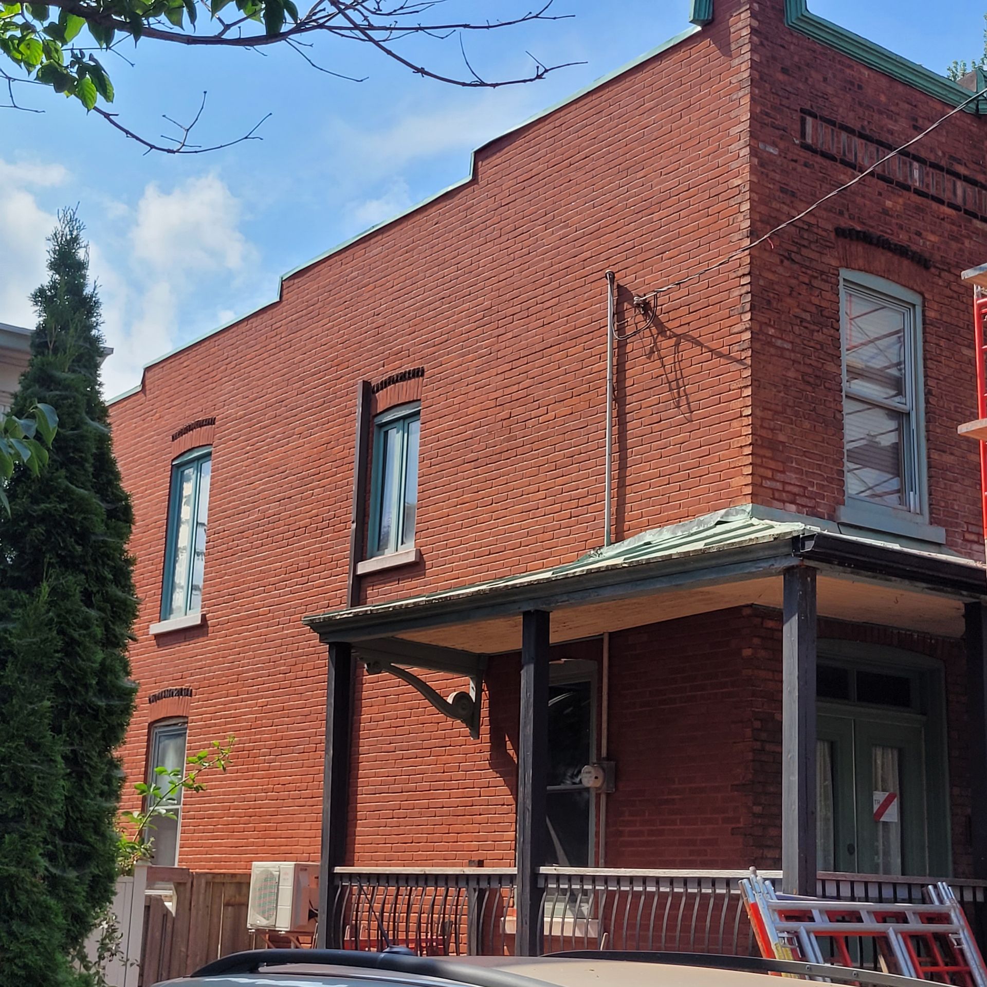 Un bâtiment en briques avec un porche et une échelle devant