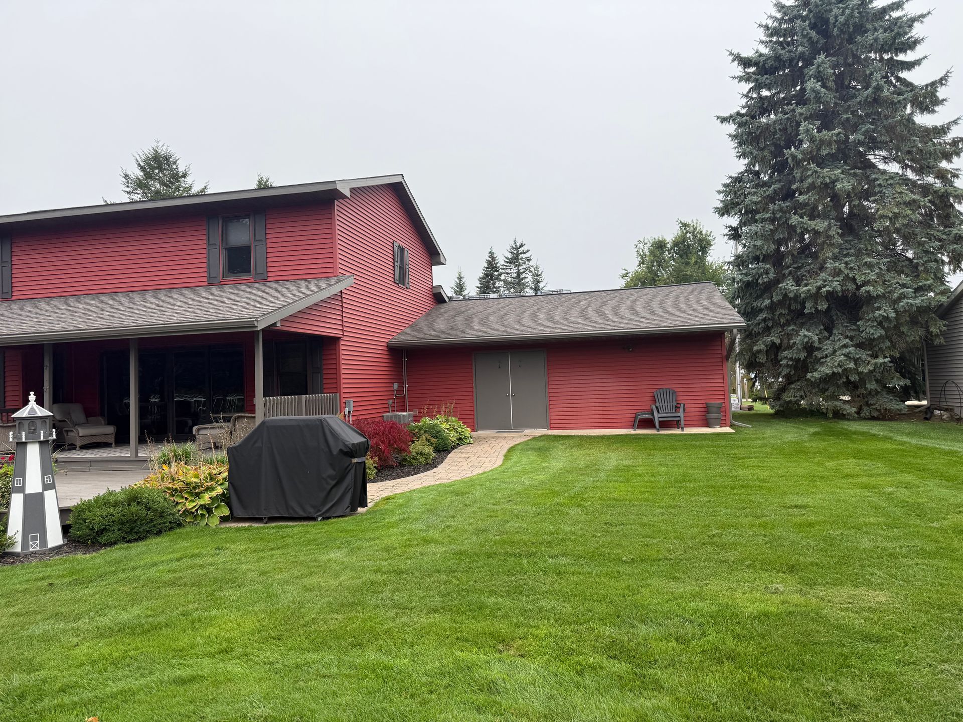 House with red siding and a new asphalt roof installation in Gaylord, MI