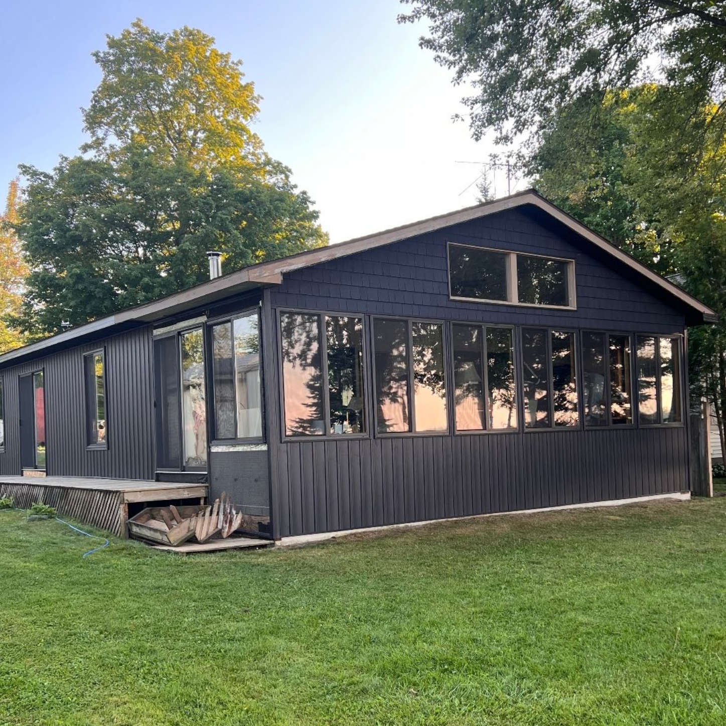 A modern, dark-sided cabin in Michigan with many windows installed on two sides.