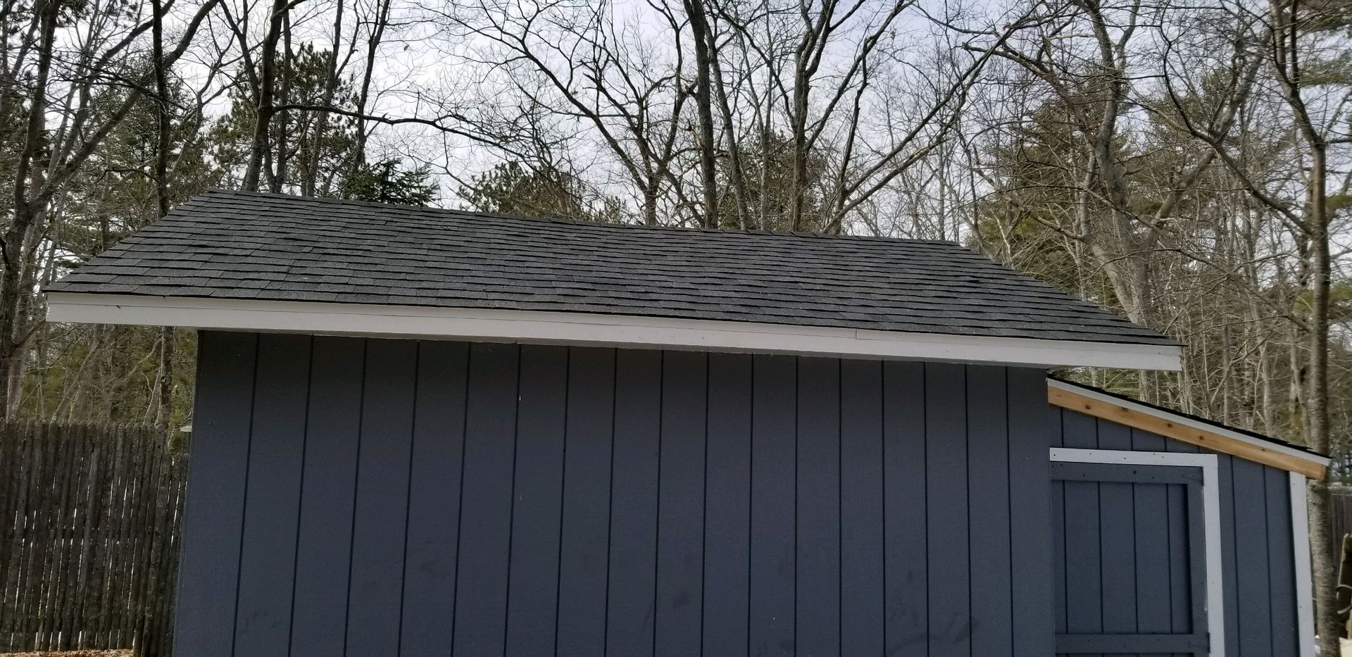 Side view of a shed in Gaylord, MI with new blue vinyl siding and a dark grey asphalt roof