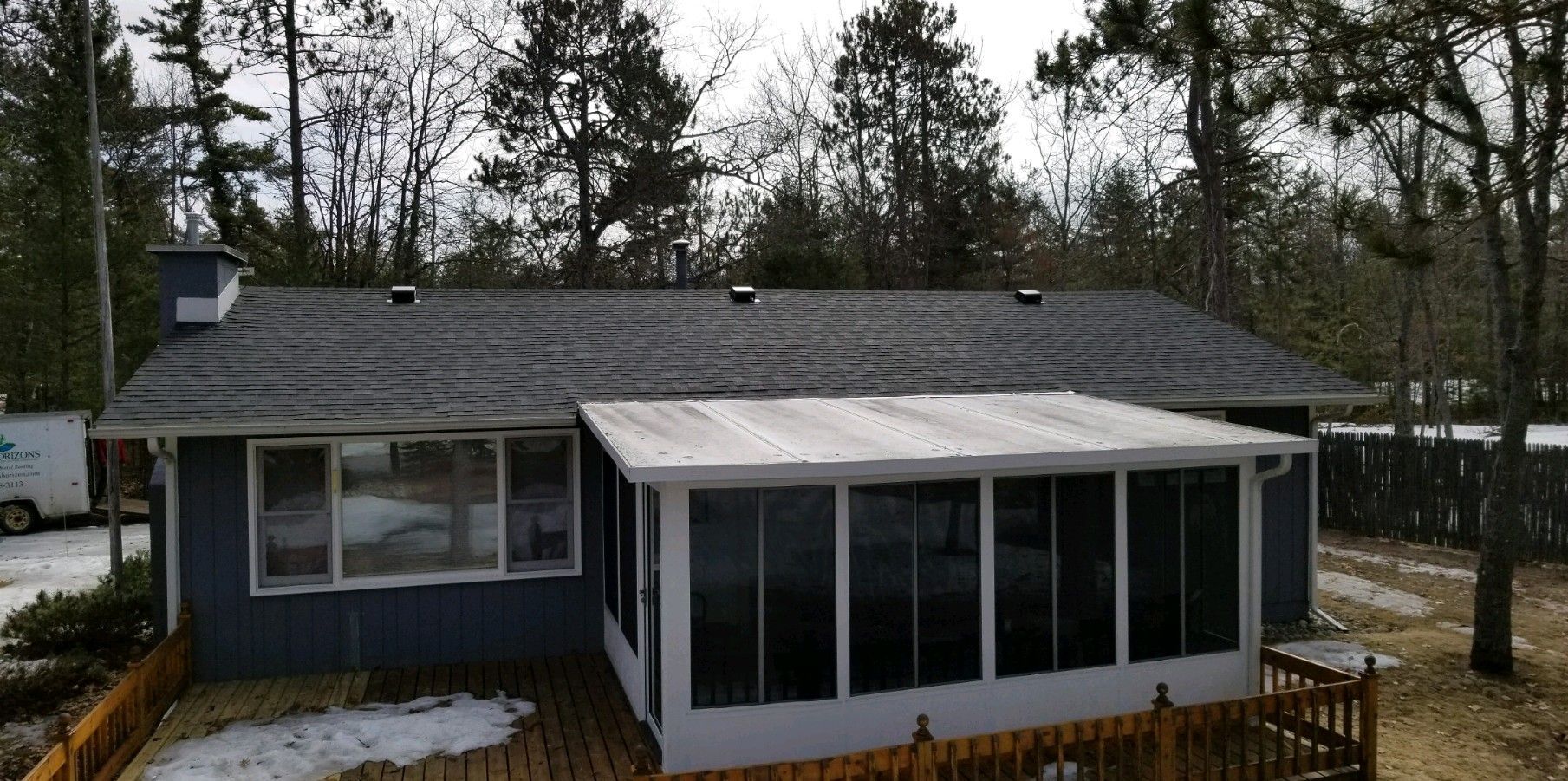 Aerial view of a house with a new asphalt roof and dark blue siding installation in Gaylord, MI