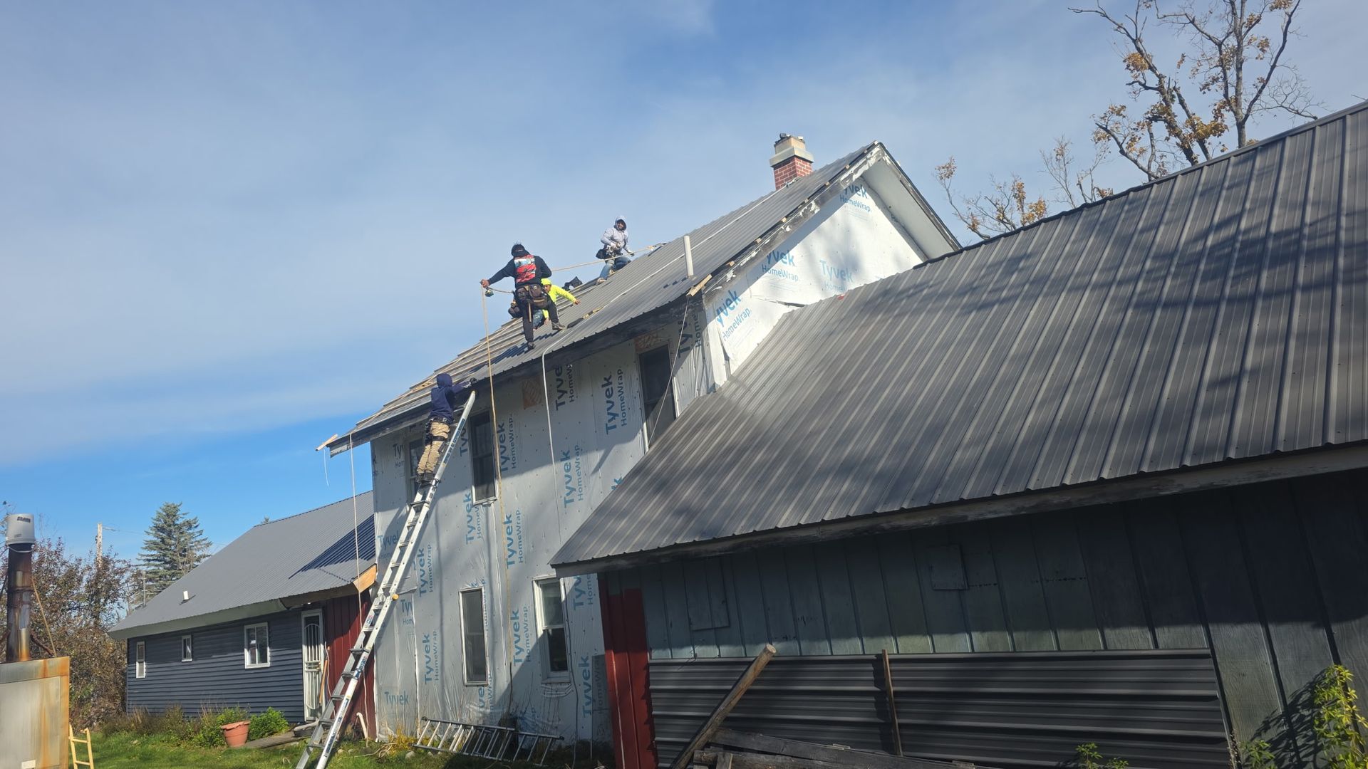 Alpine Brothers Construction team installing a residential metal roof and replacing vinyl siding in Gaylord, MI.
