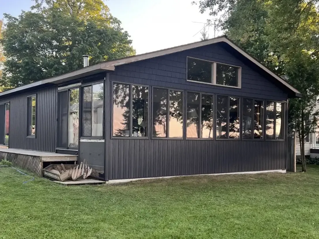 A modern, dark-sided cabin in Michigan with many windows installed on two sides.