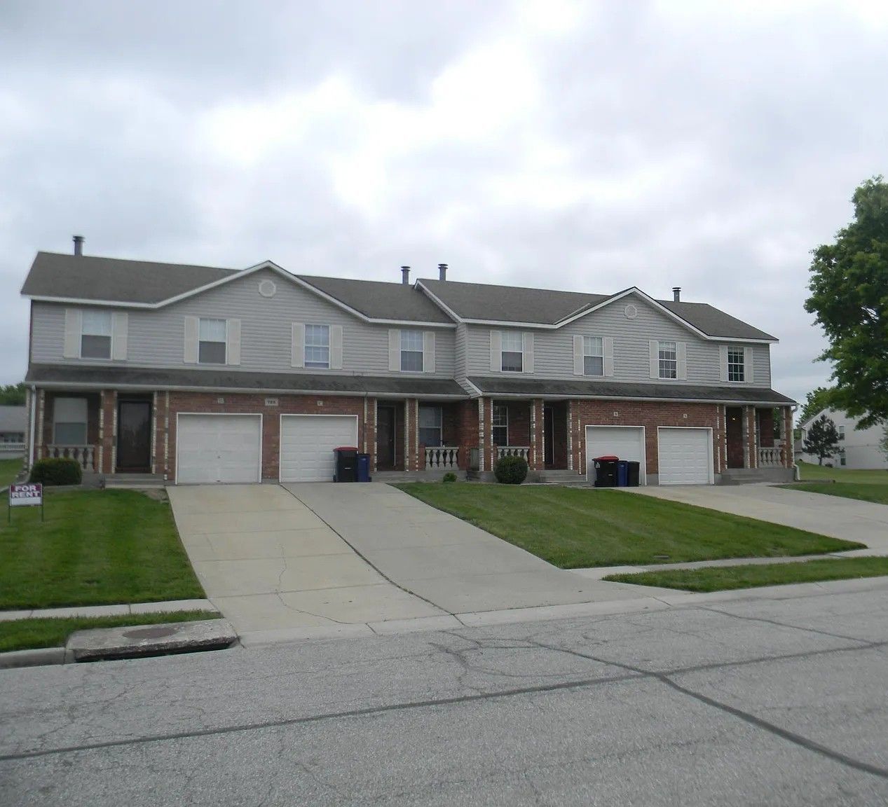 A row of houses with white garage doors on a cloudy day