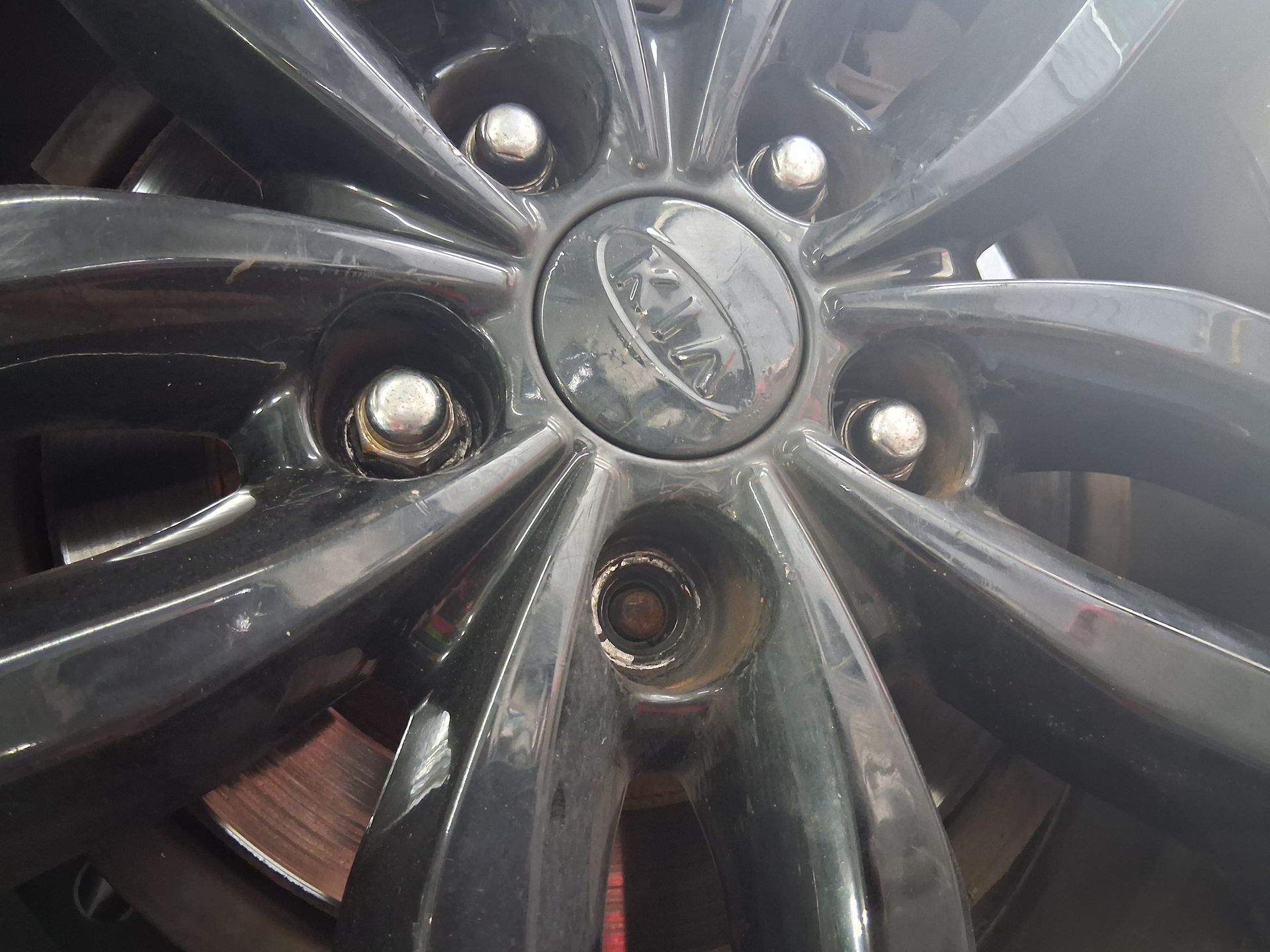 Auto mechanic replacing a broken wheel stud during a vehicle safety inspection at Small World Auto.