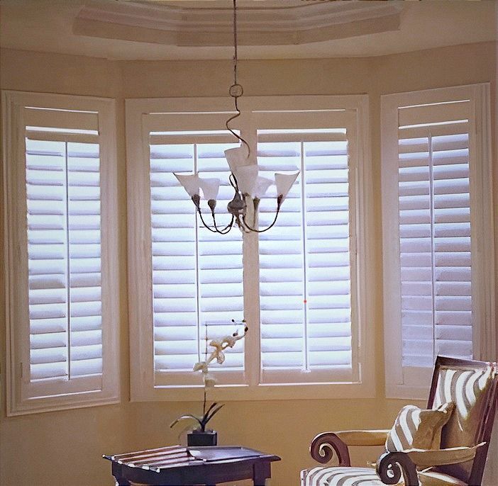 A living room with white shutters and a chandelier