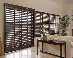 A room with three windows with wooden shutters on them.