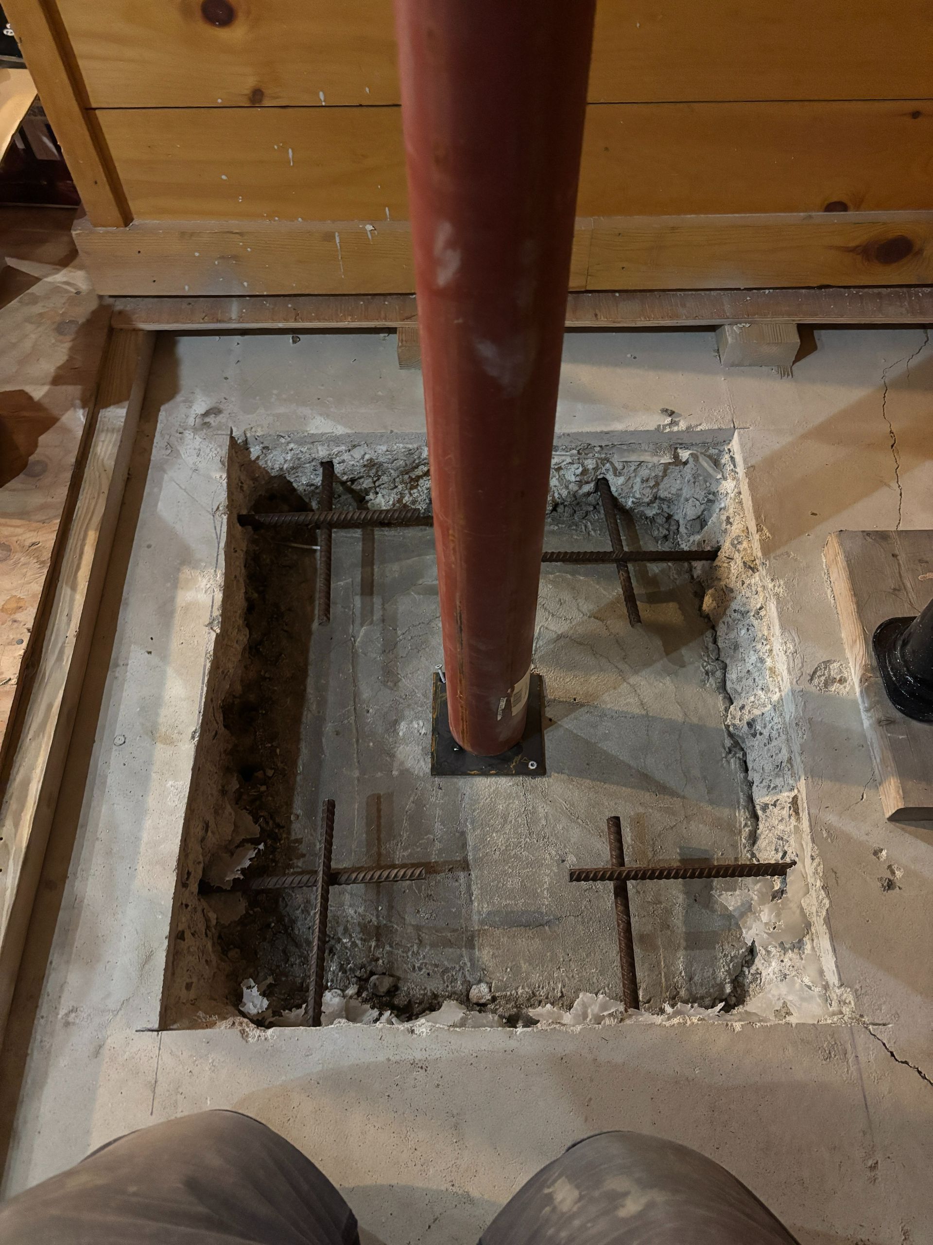 A red pipe is coming out of a hole in the floor