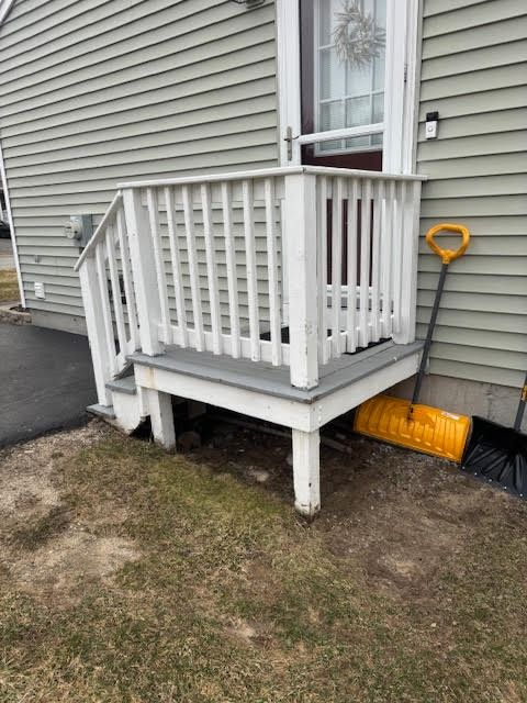 A porch with stairs and a snow shovel in front of a house.