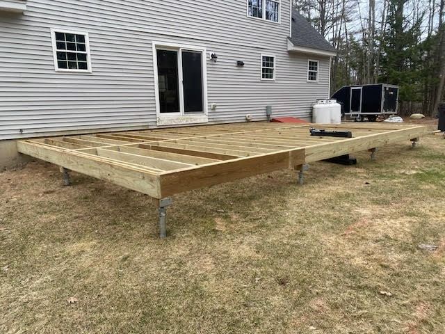 A wooden deck is being built in front of a house.
