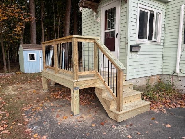 A wooden deck with stairs leading up to the front door of a house.