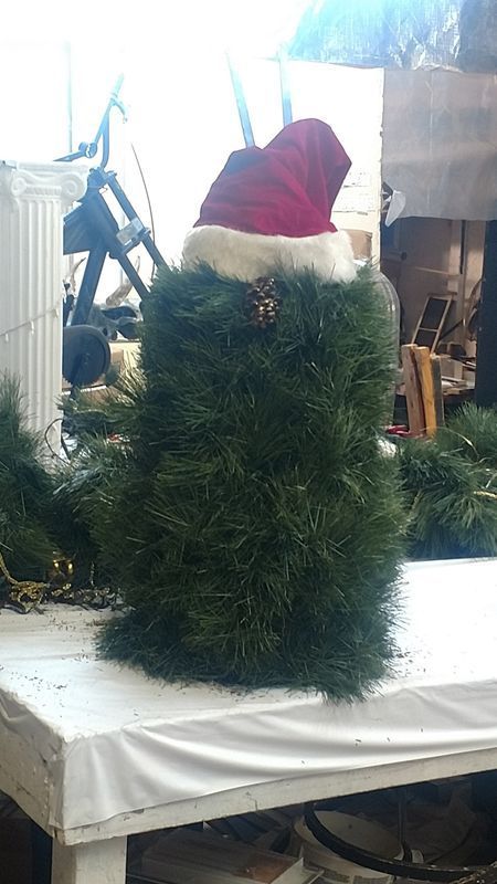 A santa hat is sitting on top of a pile of pine branches
