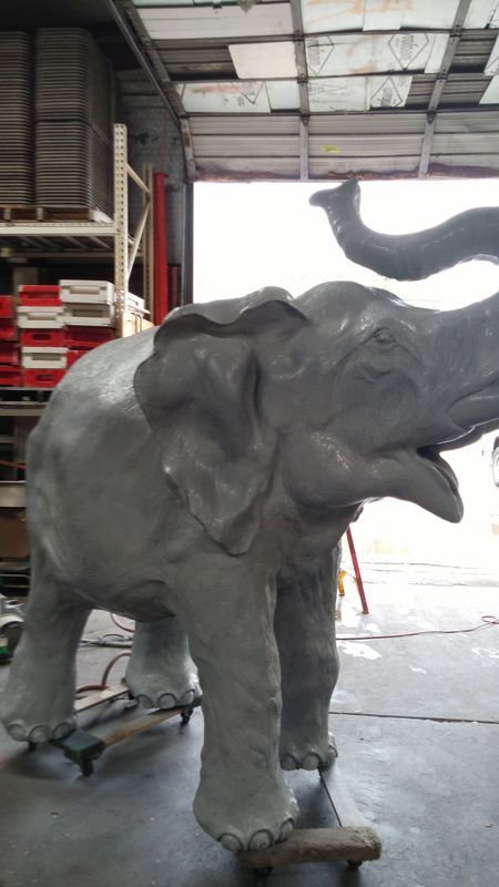 A large statue of an elephant is standing in a warehouse