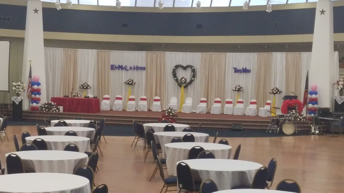 A large room with tables and chairs set up for a wedding reception
