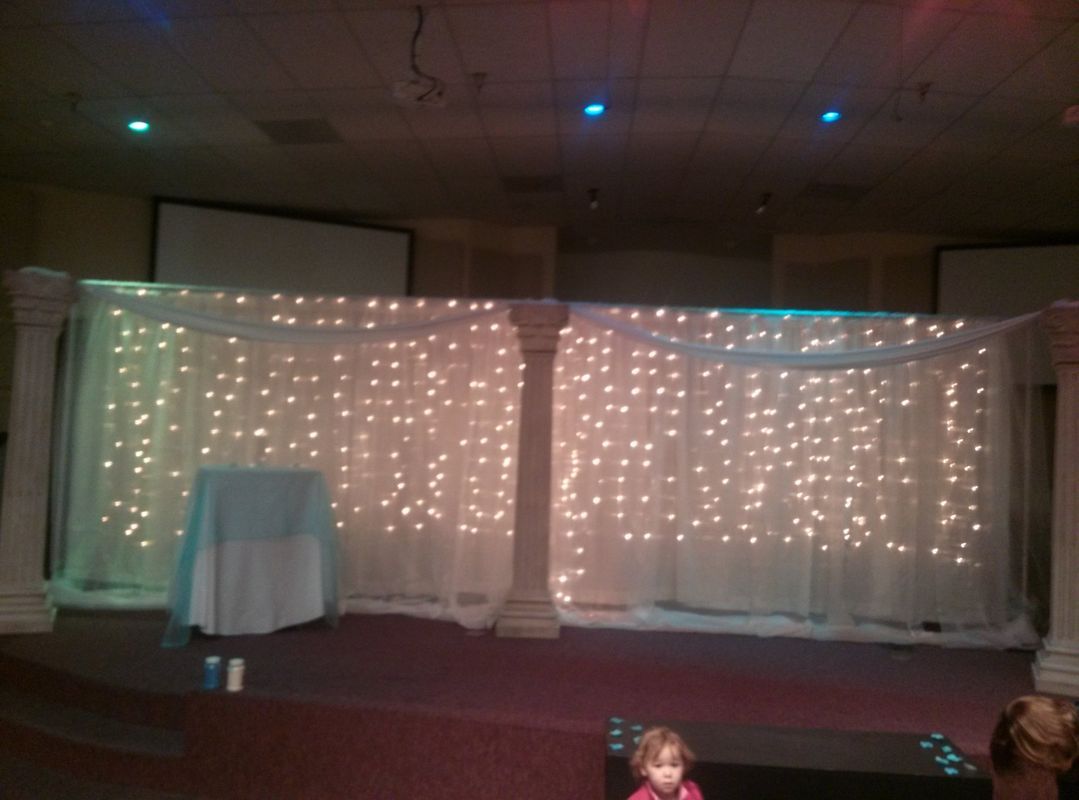A little girl is standing in front of a stage with lights on it